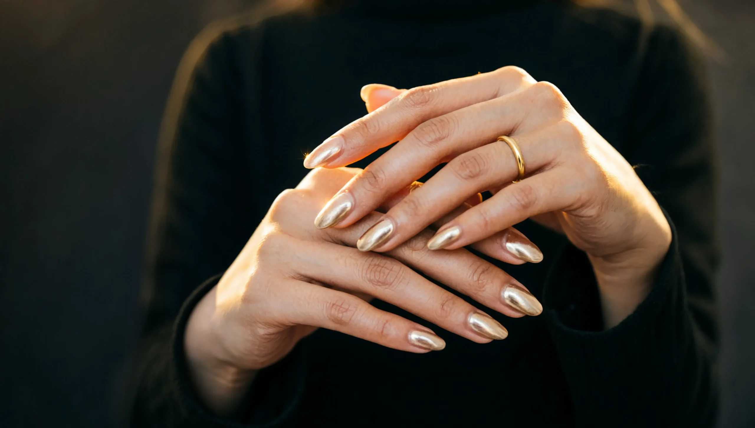 Elegant hands with glossy champagne gold chrome almond nails at Rush Salon, a nail salon in Surat