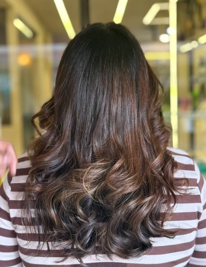 Client with medium-length layered hair and soft waves at Rush Salon, Surat