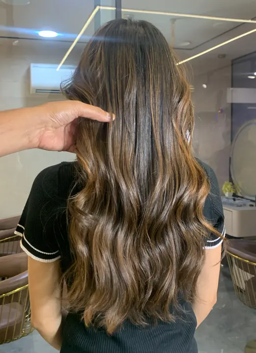 Colourist examining previously coloured hair before a colour correction at Rush Salon, Surat