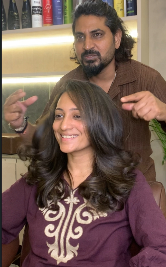 Client showing reference photos for face-framing layers at a hair cutting salon in Surat